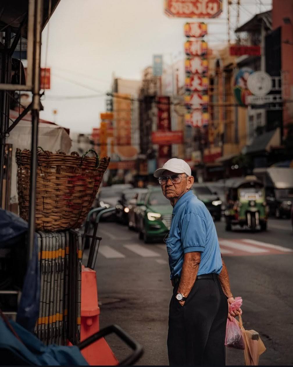 Vecino en una calle de Chinatown, Bangkok, entre comercios y letreros.